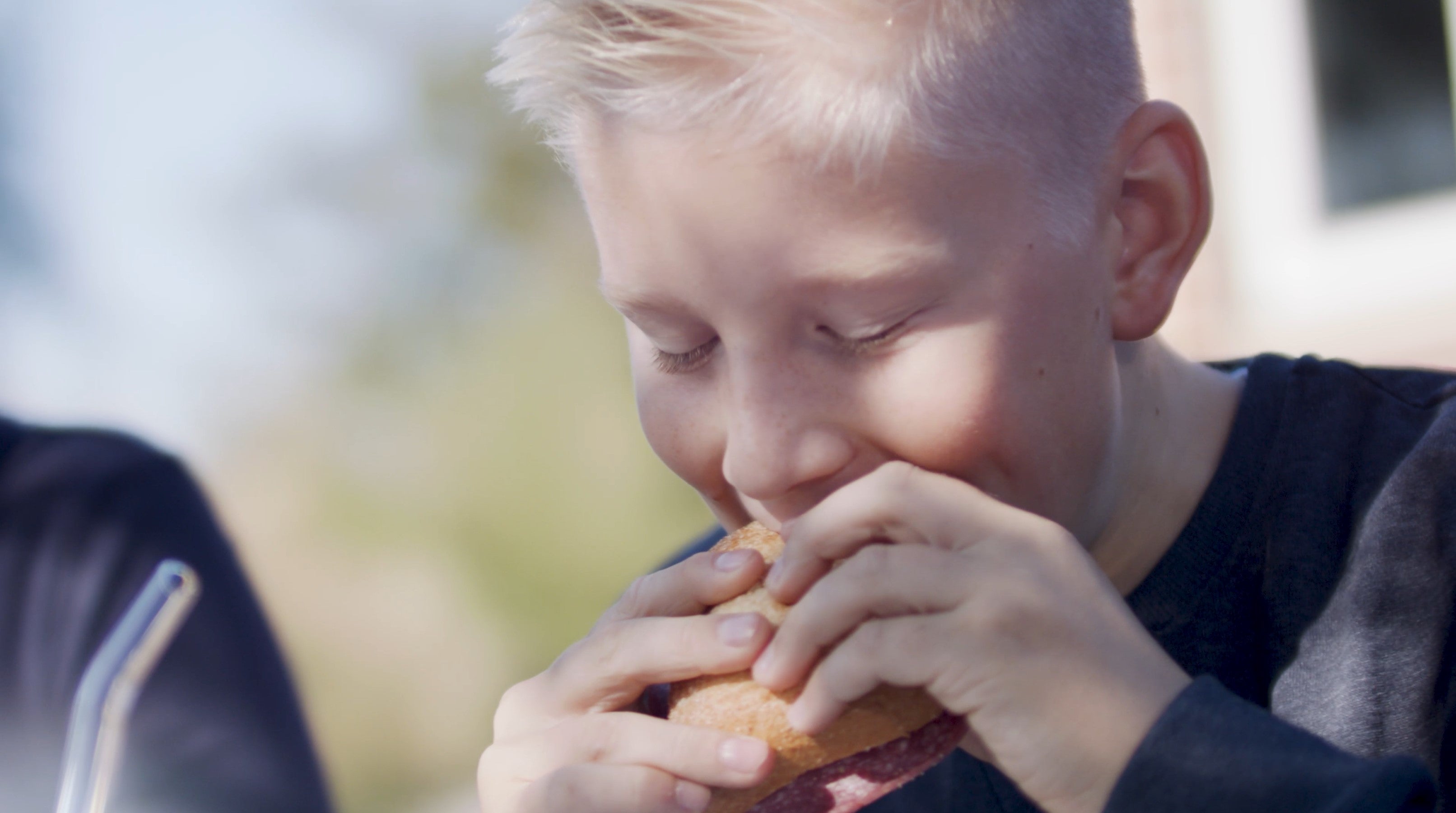 SmacoGlas Genuss - Junge beißt voller Lust ins frische, knusprige Brötchen