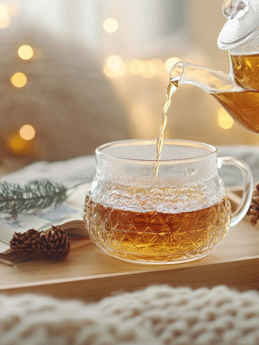 Glastasse mit heißem Tee, Zitrone und Kräutern auf Holztisch – wohltuender Teegenuss mit natürlichem Flair