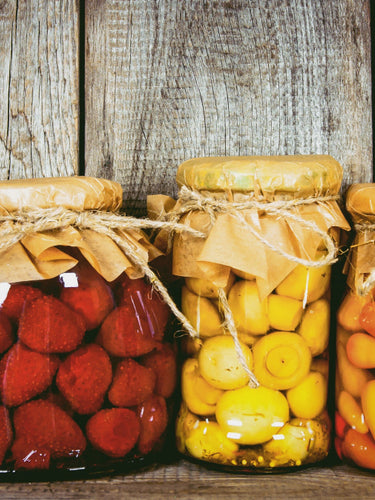 Vorratsgläser mit eingekochten Früchten und Gemüse auf Holzregal – nachhaltige Aufbewahrung für bewusste Vorratshaltung
